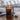 Candle in a glass holder with a visible brand logo, placed on a wooden surface with a blurred background.