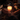 Two people holding hands over a lit candle at a romantic dinner setting.