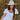 Woman wearing a white dress and cowboy hat sitting in a field of dry grass.
