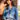 Woman wearing a cowboy hat, blue denim shirt, and jeans with a bolo tie outdoors.
