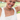 A smiling woman wearing layered pearl necklaces, a turquoise beaded necklace, gold hoop earrings with blue stones, and a white sleeveless top, photographed outdoors with a blurred green background.