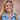 Smiling woman wearing layered Claudia baroque pearl tin cup necklaces with a denim jacket
