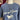 Blue sweatshirt with 'Johnny & James' design on a mannequin against a flag background