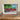 Framed painting of a red building on a wooden surface