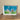 Framed picture of a city skyline on a wall next to a wooden surface.