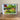 Framed picture of a scenic landscape with trees and a building on a wall.