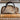 Leopard print handbag on a book with a framed painting of a landscape in the background.