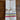 A folded white linen tea towel with colorful horizontal stripes near the bottom, tied with natural jute twine on a dark wooden background.