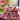 Pink fabric bundle with white ribbon on a table with flowers in the background