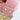 A close-up of a light pink pebbled leather belt with a gold-tone metal buckle and matching gold-tone rivets on the strap.