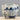 A small ceramic cup or teacup with a blue and white landscape hand-painted design, shown on a light wooden surface against a neutral gray background.