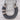 A handmade horseshoe-shaped necklace or pendant made from dark gray and black textured fur, featuring natural tan fur accents and a black leather loop at the top, displayed on a light gray wood background.