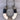 A handmade horseshoe-shaped pendant necklace made from natural cowhide and wrapped with black and cream yarn, shown on a gray wood background.