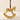 A small gold-toned rocking horse ornament with a dark brown hanging ribbon, photographed against a soft warm beige background.