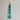A beaded necklace with turquoise and green beads hanging from a brass wall hook against a plain light gray background.