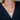 Close-up of the Tillie coin and gold bar pendant on a paperclip chain, worn with a black V-neck top