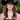 Woman wearing a black cowboy hat and layered necklaces against a blurred natural background